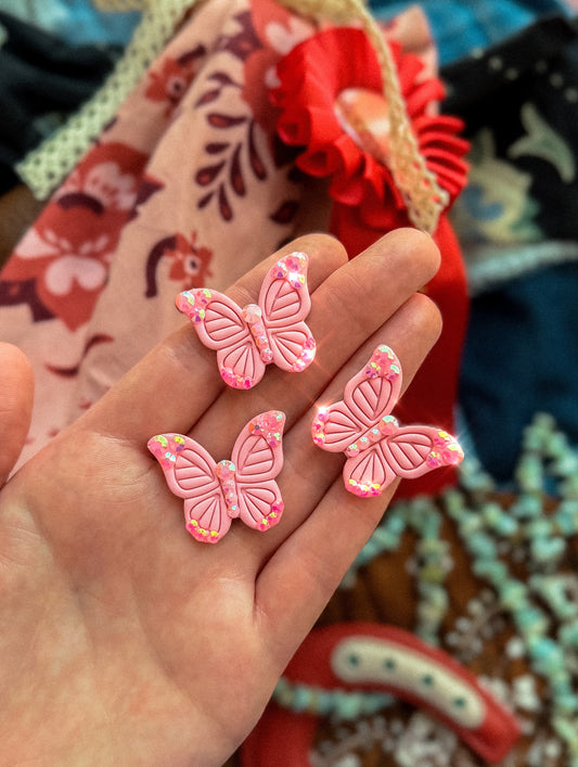 Three pink rhinestone butterfly pins with sparkling crystal details displayed in hand