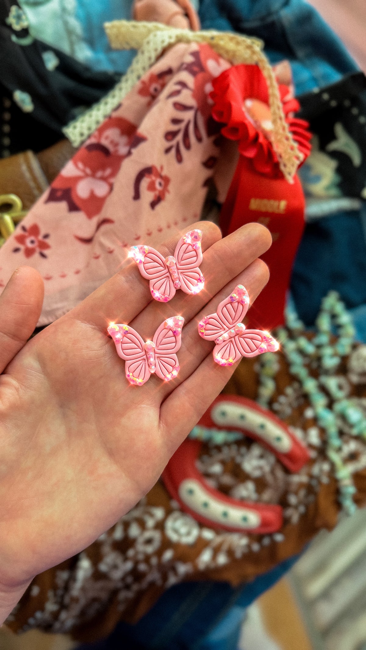 Three pink butterfly brooches with rhinestone accents shown in hand for size and scale