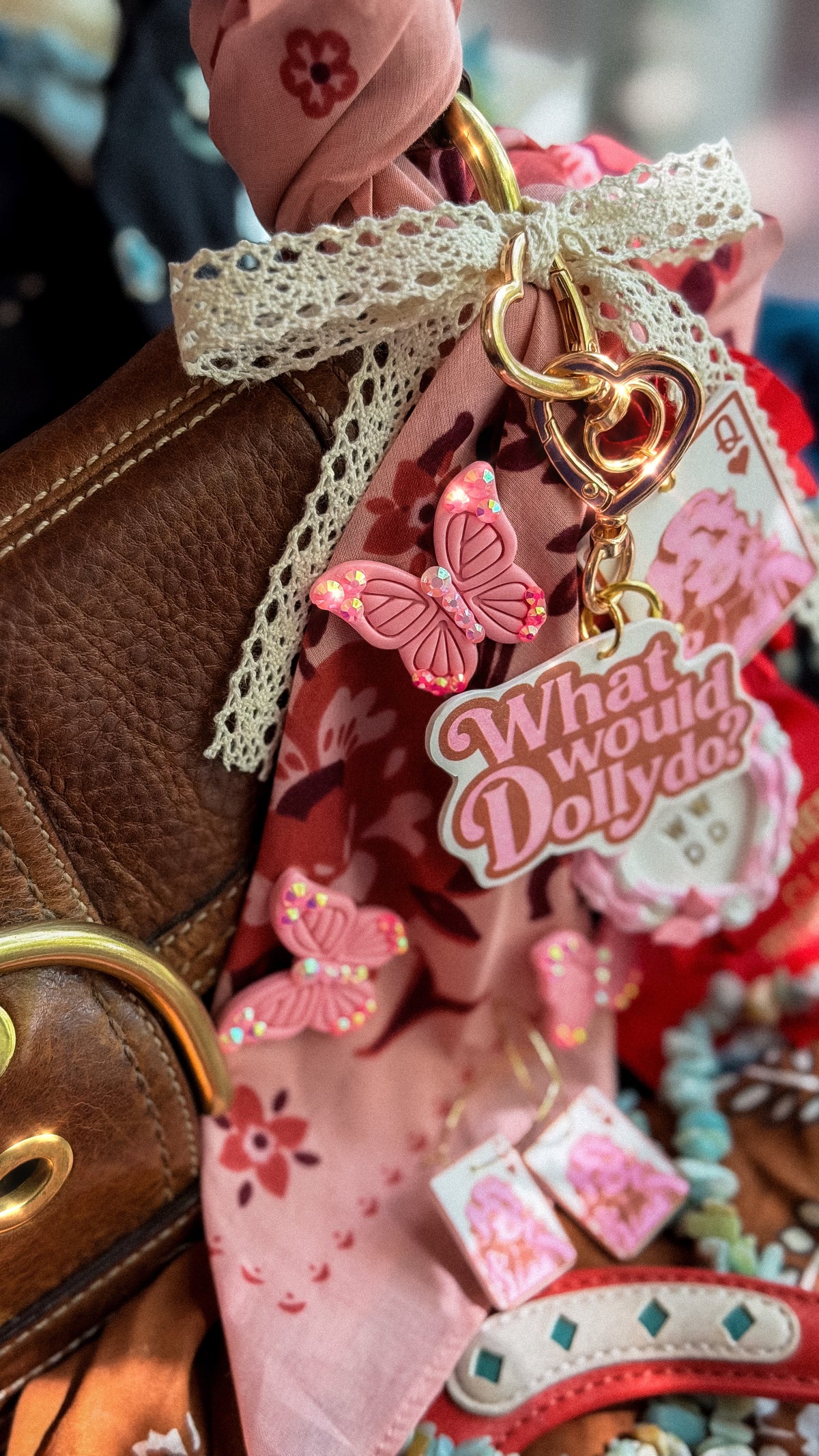 Pink rhinestone butterfly brooch styled on a purse with What Would Dolly Do bag charm and Queen Dolly accessories