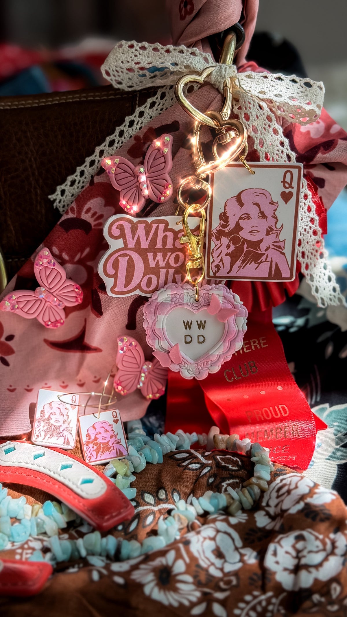 Dolly Parton inspired WWDD heart bag charm styled with pink butterflies, Queen Dolly card charm and western accessories