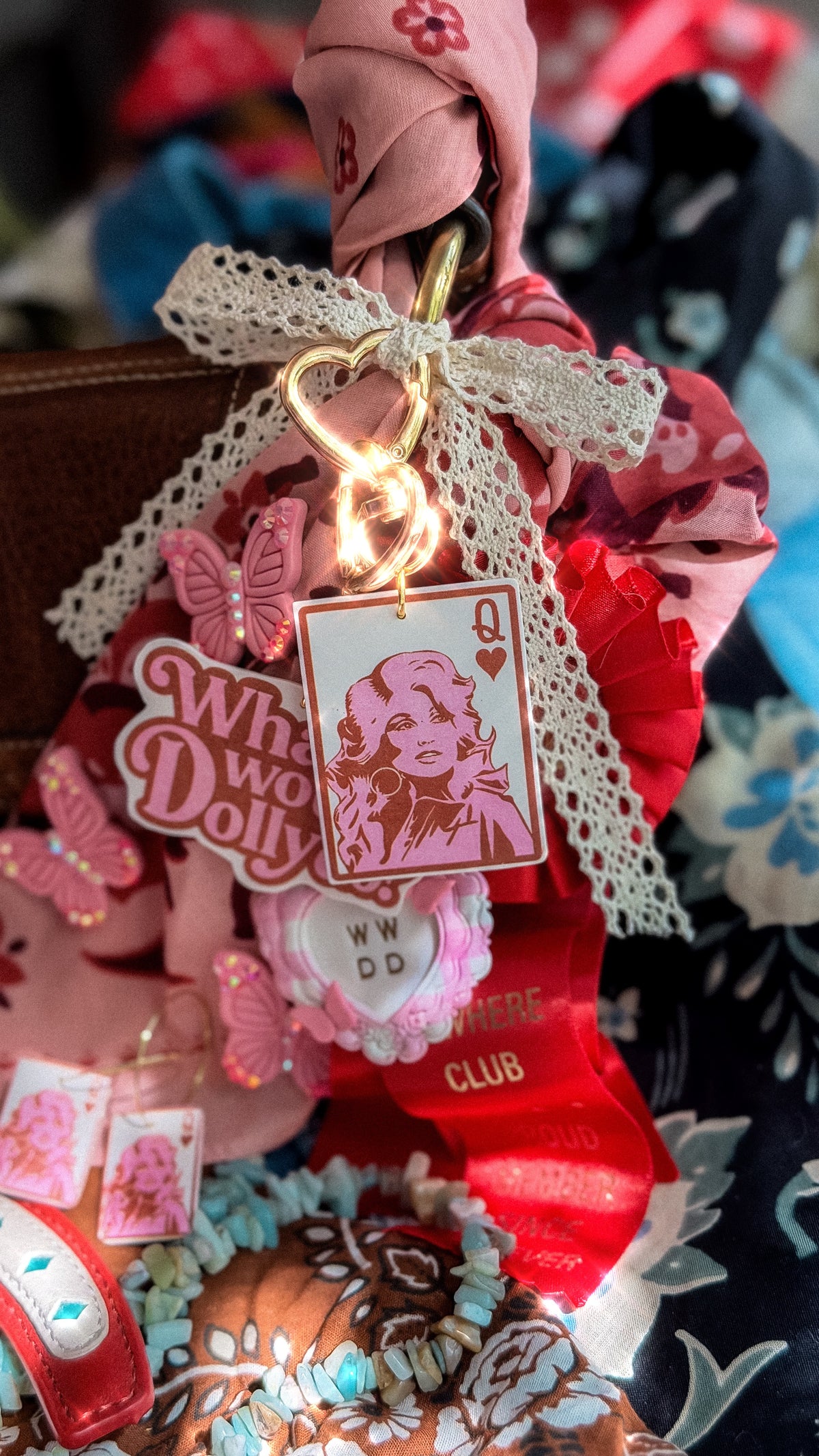 Close-up of pink Queen Dolly Queen of Hearts bag charm with gold heart clasp and lace ribbon